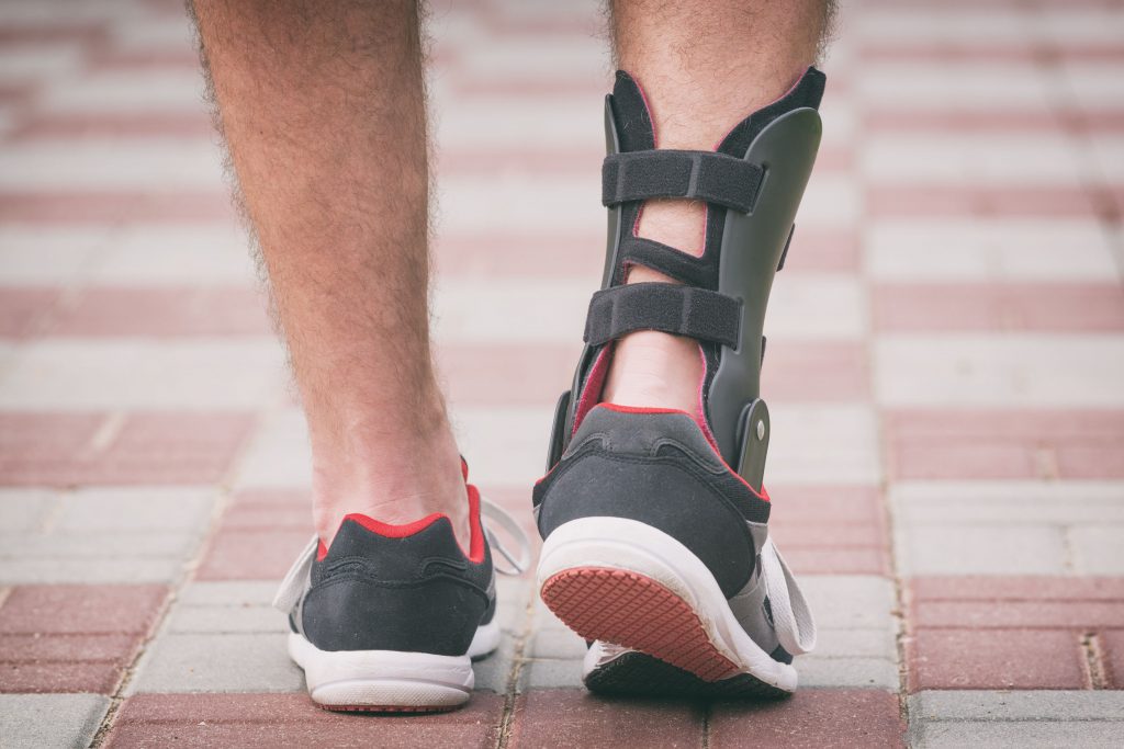 man in athletic sneakers wearing ankle orthosis or brace